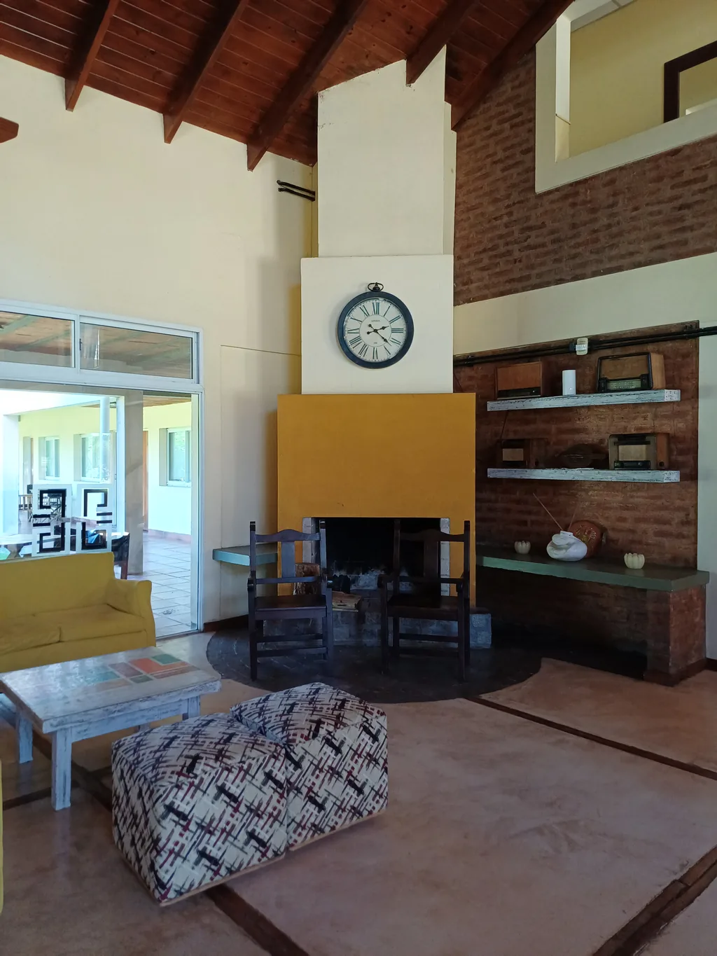 Living con hogar a leña, sillones y reloj de pared